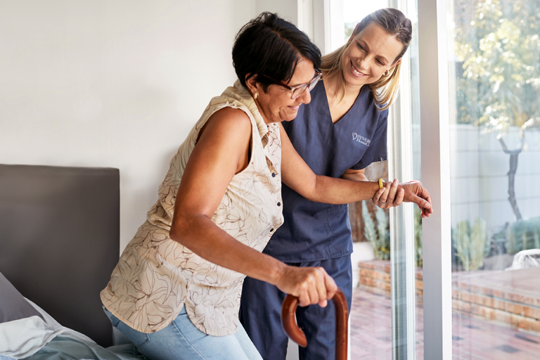 A caregiver helps a client get up and walk