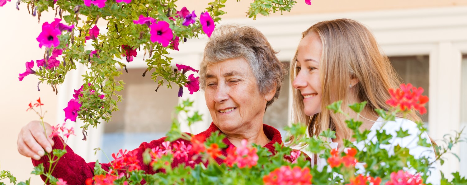 Elderly woman shows her flowers to her assistant