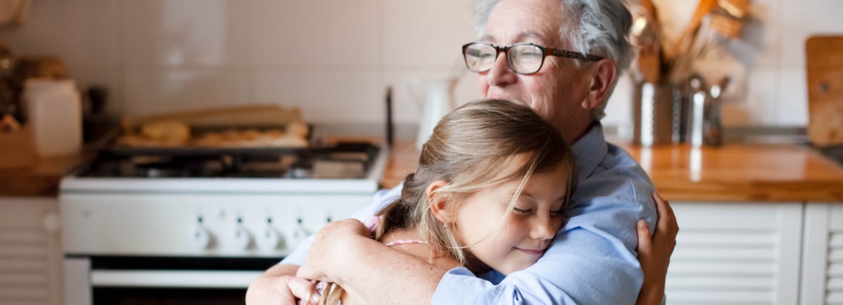 Grandmother hugging her granddaughter and smiling.