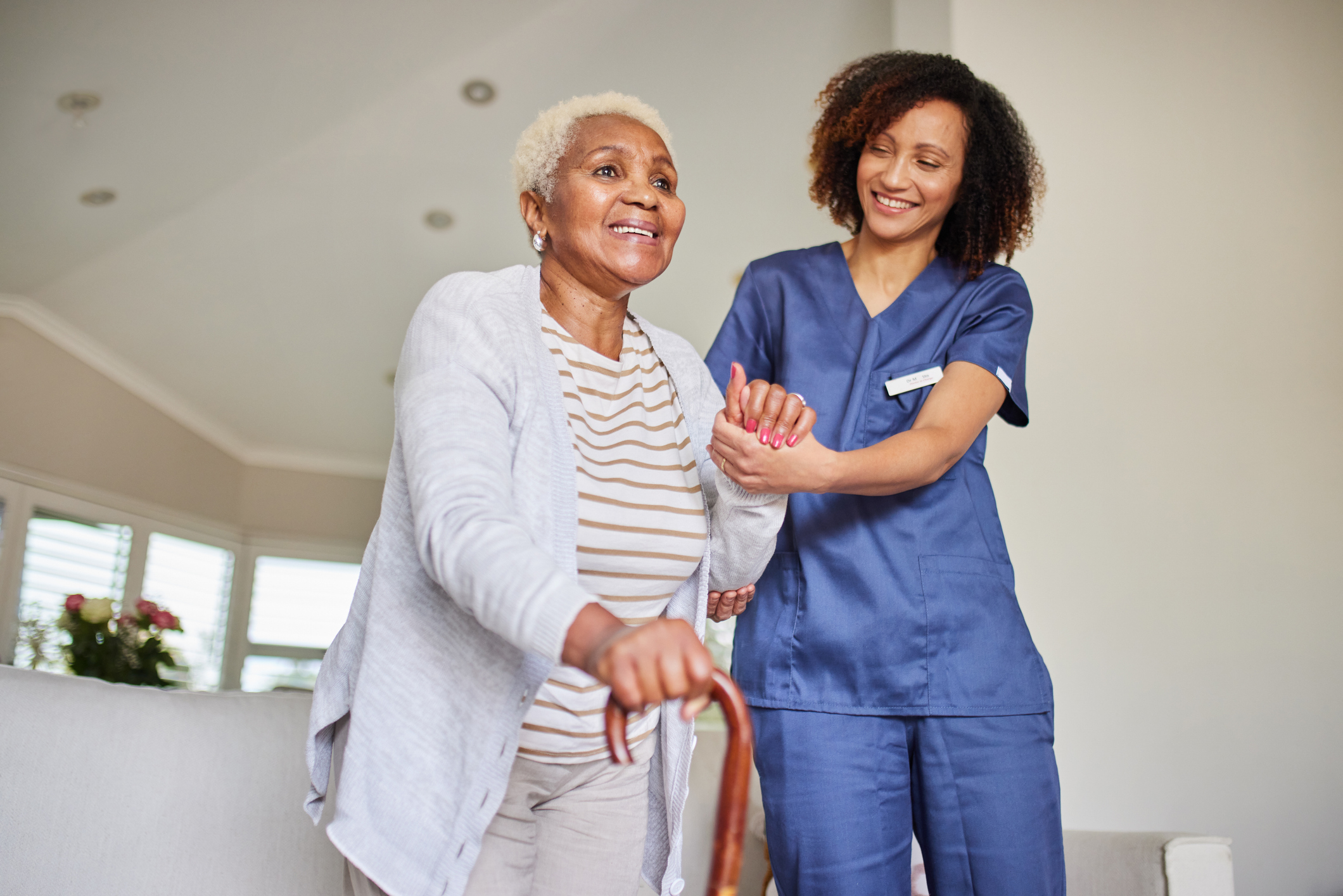 SYNERGY HomeCare caregiver helping client walk.