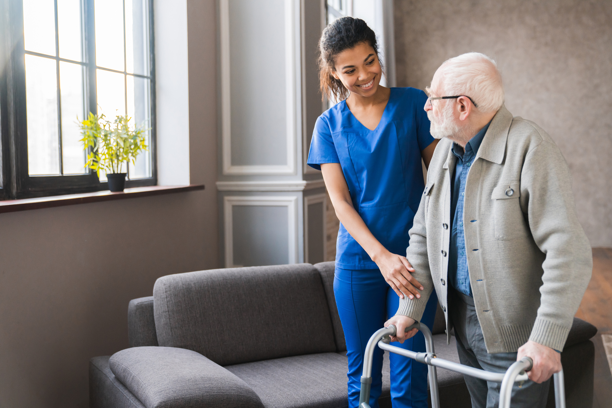 SYNERGY HomeCare caregiver helping client walk