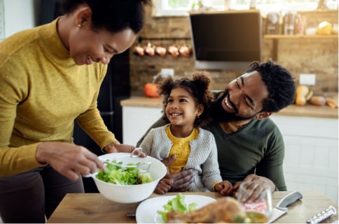 Young family sitting down at the dinner table getting ready to eat and smiling.