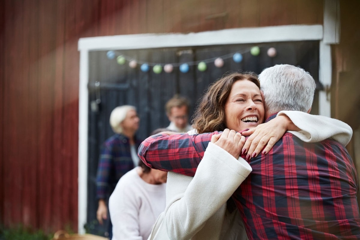 Happy mature woman embracing man while standing at farm