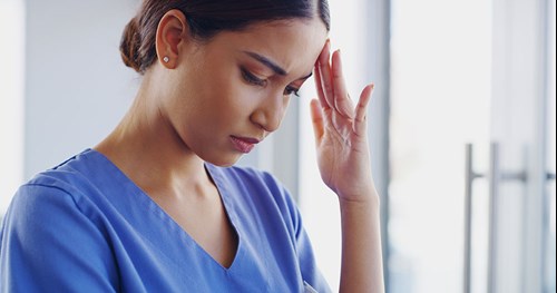 caregiver female with head tilted down and fingertips supporting head eyes closed sad