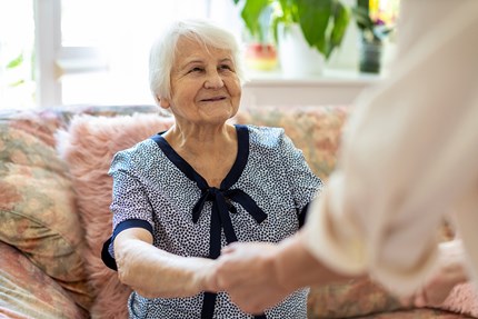 happy senior woman holding caregiver's hands