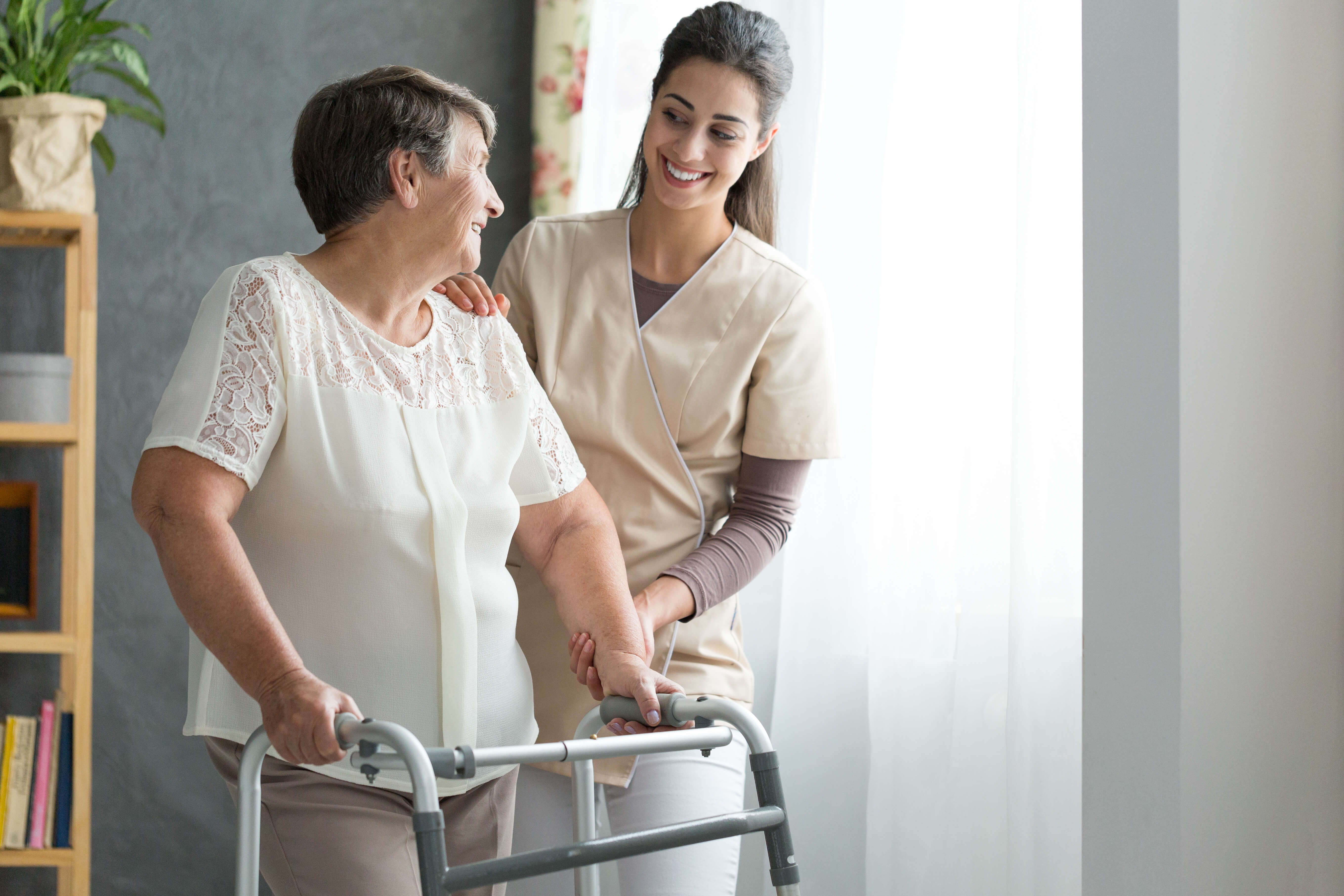 senior woman in walker being helped by caregiver for seniorspost hospital recovery