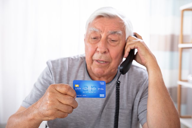 senior man on phone reading his credit card info to person on phone