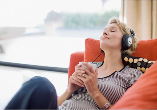 woman-relaxing-with-drink-listening-to-headphones