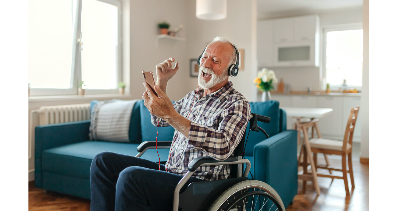 senior man in wheelchair enjoying listening to music as he looks at his smart phone