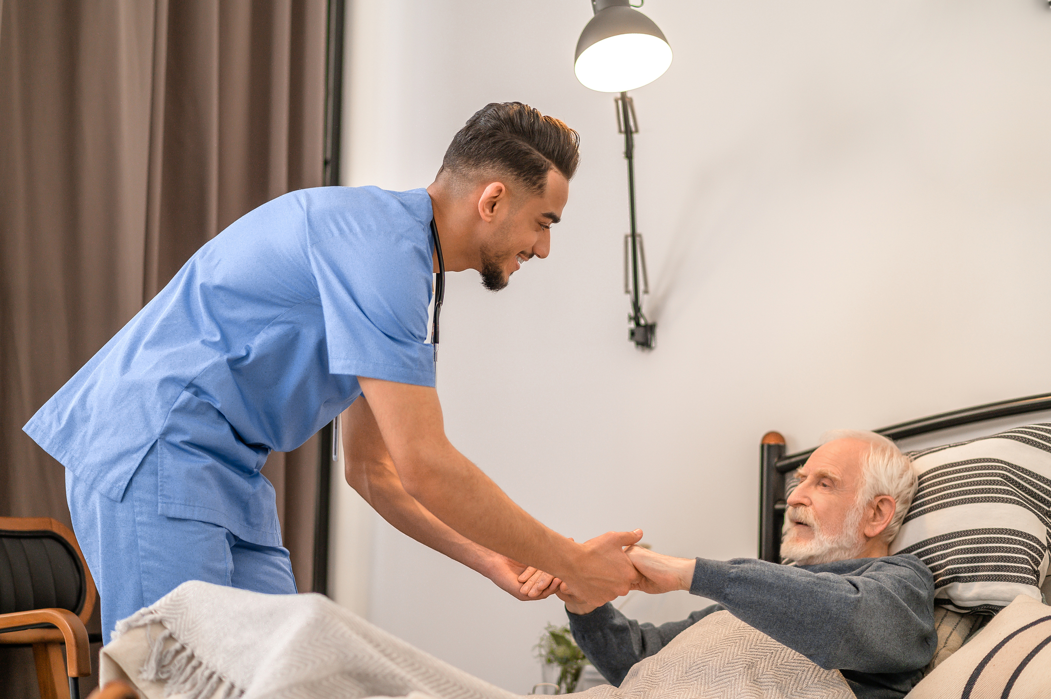 caregiver helping senior out of bed