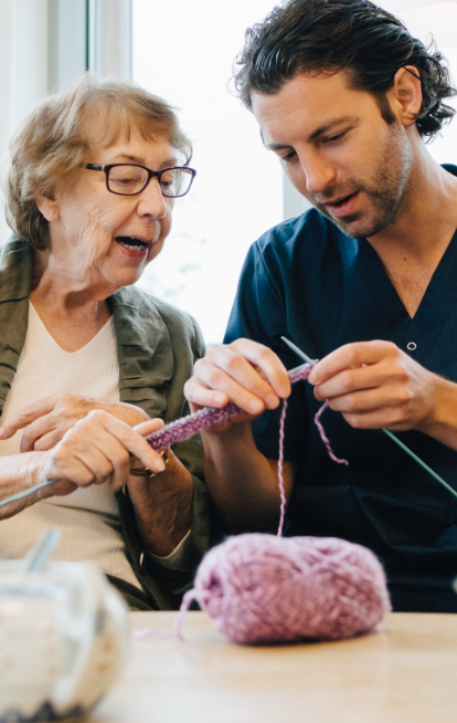 senior woman and care taker knitting together