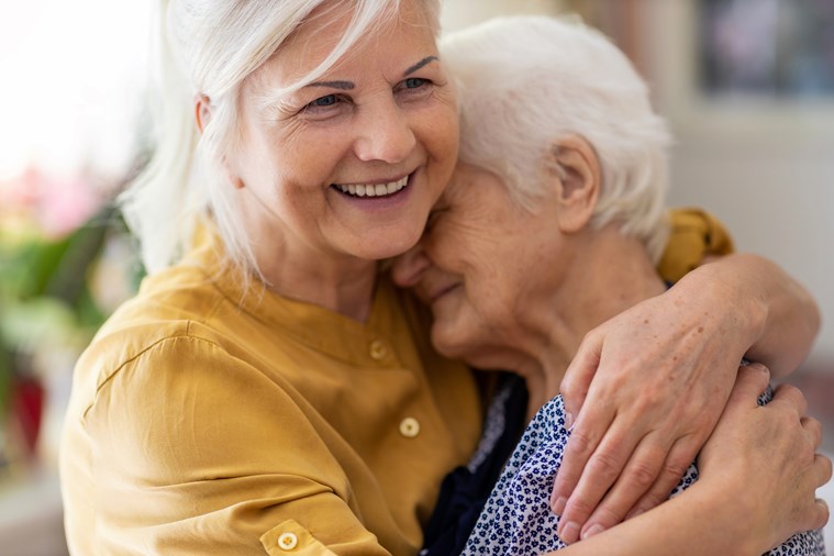 adult daughter hugging senior mom