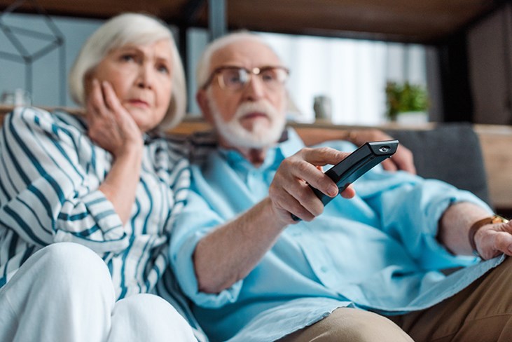 senior couple on couch watching tv