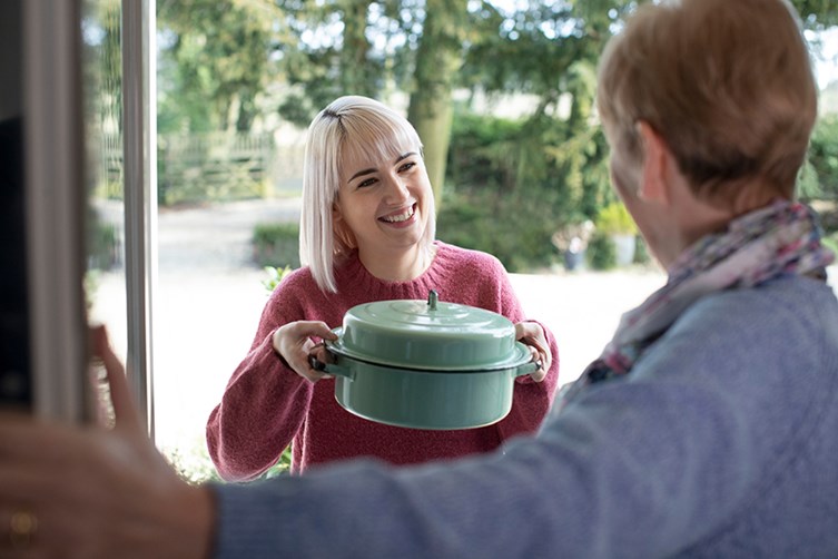 neighbor taking caserole to senior neighbor